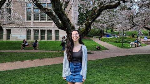 young woman stands under cherry tree on campus
