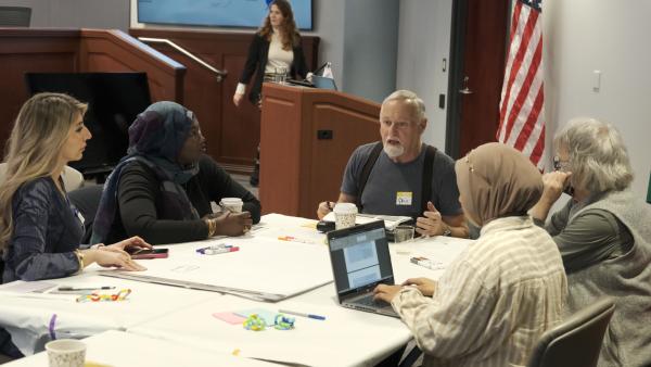 Group of people gather around a table and discuss