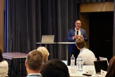 man speaking in front of people sitting at tables
