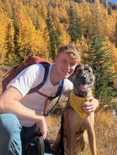 Man smiling with dog with trees in the background